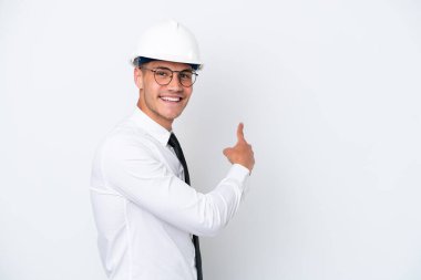 Miğferli ve elinde beyaz arka planda izole edilmiş planları olan genç bir beyaz adam.