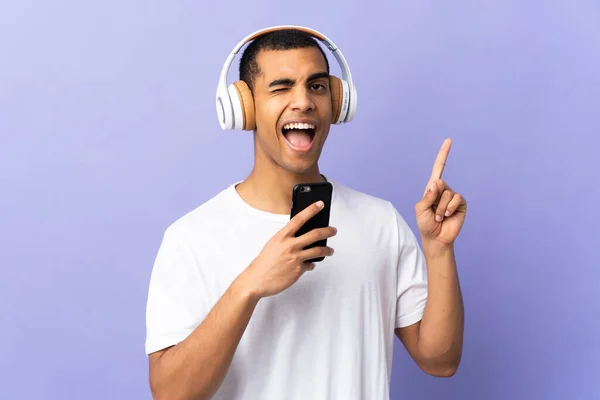 Hombre Afroamericano Sobre Fondo Púrpura Aislado Escuchando Música Con Móvil —  Fotos de Stock