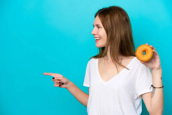 Young English Woman Holding Donut Isolated Blue Background Pointing Side — Stockfoto