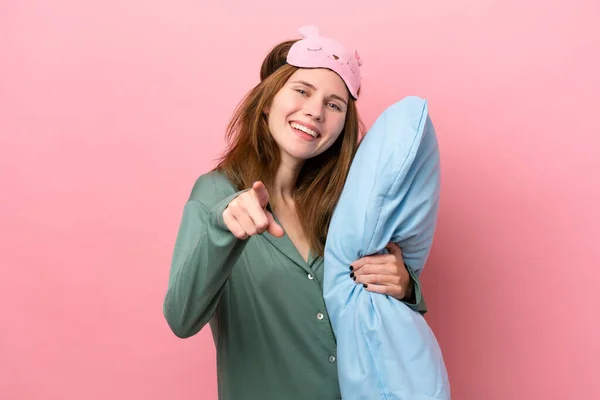 Young English woman in pajamas isolated on pink background in pajamas and points finger at you with a confident expression