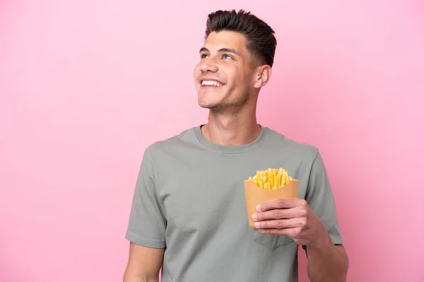 Jonge Kaukasische Man Met Gebakken Chips Geïsoleerd Roze Achtergrond Denken — Stockfoto