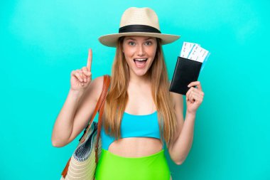 Traveler caucasian woman holding passport isolated on blue background pointing up a great idea