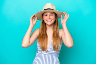 Mavi arka planda izole edilmiş genç bir kadın yaz tatillerinde mayolu mutlu.