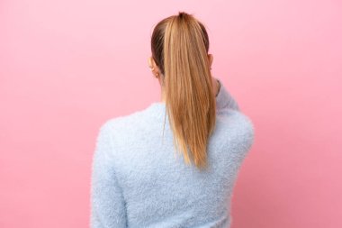 Genç beyaz kadın pembe arka planda izole edilmiş ve düşünüyor.