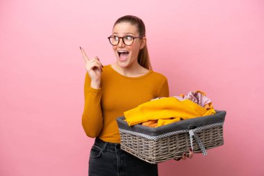 Pembe arka planda izole edilmiş çamaşır sepetini tutan beyaz bir kadın çözümün farkına varmak için parmağını kaldırıyor.