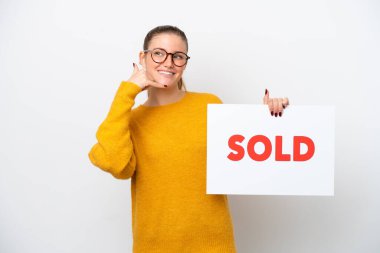 Beyaz arka planda izole edilmiş genç beyaz bir kadın. Elinde satılmış bir afiş var ve el kol hareketi yapıyor.