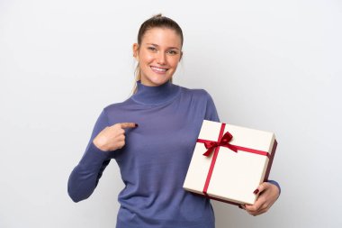 Beyaz arka planda yüzü sürpriz bir ifadeyle izole edilmiş bir hediye tutan beyaz bir kadın.