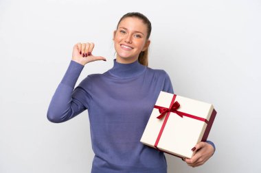 Beyaz arka planda izole edilmiş, gururlu ve kendini beğenmiş bir hediyeyi elinde tutan beyaz bir kadın.