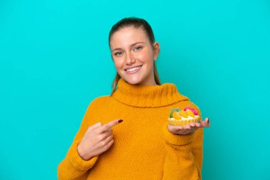 Mavi arka planda izole edilmiş bir tart tutan beyaz bir kadın.