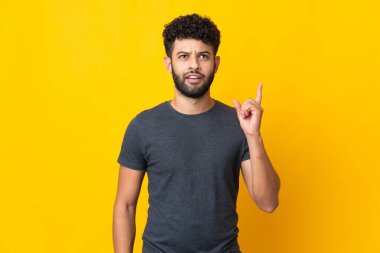 Genç Faslı bir adam sarı arka planda izole edilmiş.