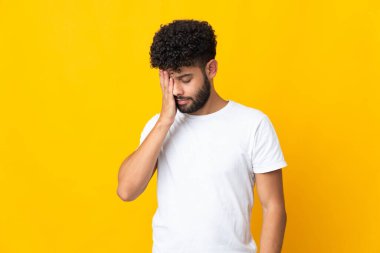 Faslı genç bir adam sarı arka planda izole edilmiş, baş ağrısı var.