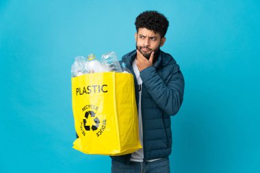 Genç Faslı bir adam, izole edilmiş arka plan üzerinde geri dönüşüm yapmak için plastik şişelerle dolu bir çanta tutuyor.
