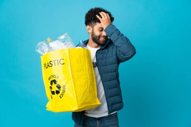Bir çanta dolusu plastik şişeyi izole edilmiş arka planda geri dönüşüm için tutan genç Faslı bir adam bir şey fark etti ve çözümü amaçladı.