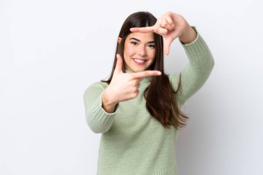 Young Brazilian woman isolated on white background focusing face. Framing symbol