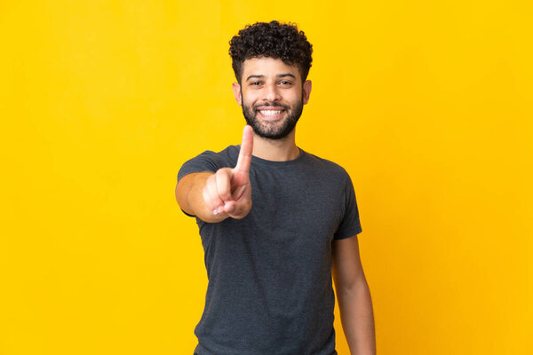 Young Moroccan man isolated on yellow background showing and lifting a finger