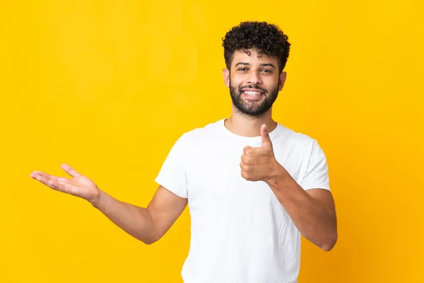 Young Moroccan Man Isolated Yellow Background Holding Copyspace Imaginary Palm — Stockfoto