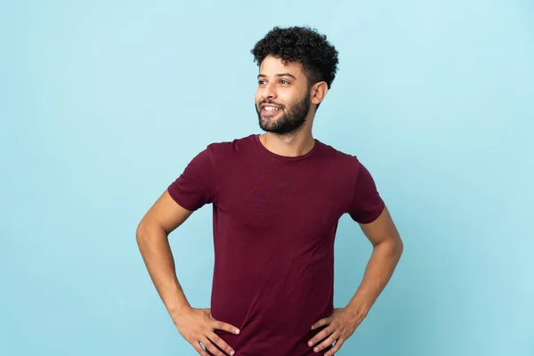 Young Moroccan Man Isolated Blue Background Posing Arms Hip Smiling — Stock Photo, Image