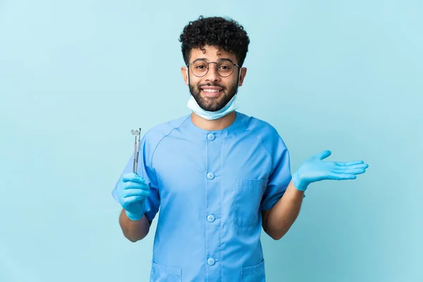 Marokański Dentysta Trzyma Narzędzia Odizolowane Niebieskim Tle Wstrząśniętym Wyrazem Twarzy — Zdjęcie stockowe