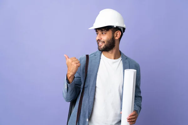 Young Architect Moroccan Man Helmet Holding Blueprints Isolated Background Pointing — стоковое фото