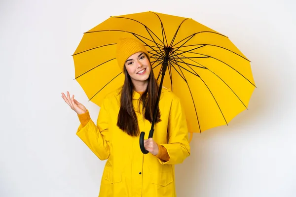 若いですブラジル人女性でレインプルーフコートと傘は白い背景に隔離されました招待状が来るために側に手を伸ばし — ストック写真