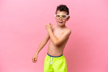 Pembe arka planda izole edilmiş dalış gözlüğü takan beyaz bir çocuk zaferi kutluyor.