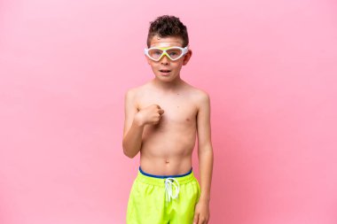 Dalış gözlüğü takan beyaz bir çocuk. Pembe arka planda izole edilmiş. Yüz ifadesi şaşırtıcıydı.
