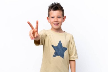 Beyaz arka planda izole edilmiş küçük beyaz çocuk gülümsüyor ve zafer işareti gösteriyor.