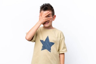 Beyaz arka planda izole edilmiş küçük beyaz çocuk, gözleri elleriyle kaplıyor ve gülümsüyor.