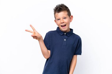 Beyaz arka planda izole edilmiş küçük beyaz çocuk gülümsüyor ve zafer işareti gösteriyor.