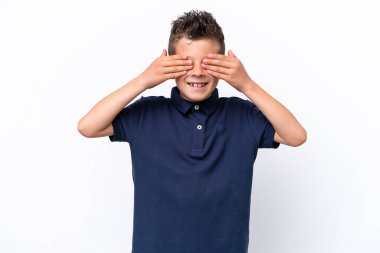Beyaz arka planda izole edilmiş küçük beyaz çocuk, gözleri elleriyle kaplıyor ve gülümsüyor.