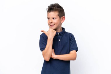 Beyaz arka planda izole edilmiş küçük beyaz çocuk bir ürünü sunmak için kenarı işaret ediyor.