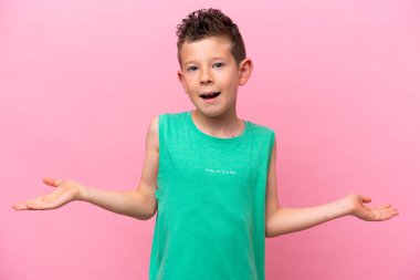 Küçük beyaz çocuk pembe arka planda izole edilmiş, şok olmuş bir yüz ifadesi var.