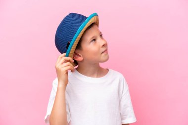 Pembe arka planda izole edilmiş şapka takan beyaz bir çocuk.