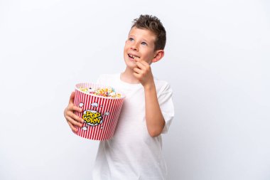 Beyaz arka planda izole edilmiş küçük beyaz çocuk elinde koca bir kova patlamış mısır tutuyor.