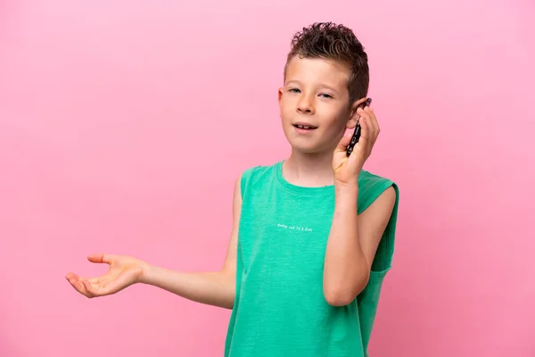 一个被粉色背景隔离的高加索小男孩在和别人用手机聊天 — 图库照片