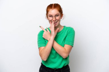 Beyaz arka planda izole edilmiş genç bir kadın bir ürün sunmak ve bir şeyler fısıldamak için kenarı işaret ediyor.