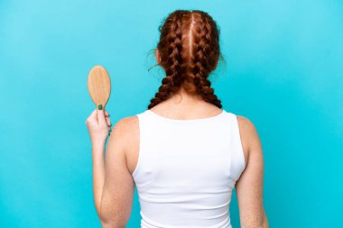 Saçları taranmış beyaz, genç bir kadın arka planda mavi arka planda izole edilmiş.