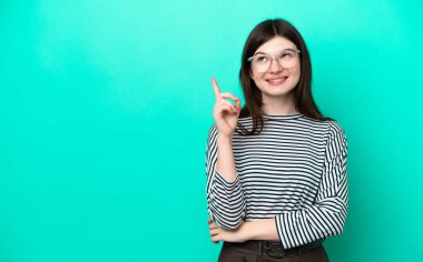 Yeşil arka planda izole edilmiş genç Rus kadın harika bir fikre işaret ediyor.