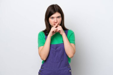 Mavi arka planda izole edilmiş genç bir Rus kadın sessizlik işareti gösteriyor.