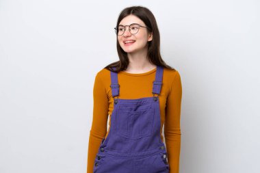 Genç Rus kadın mavi arka planda izole edilmiş, yan tarafa bakıyor ve gülümsüyor.