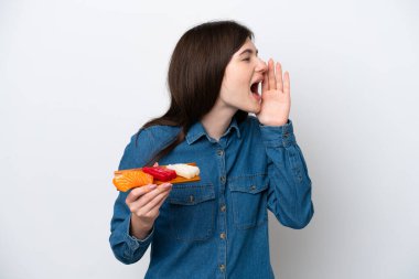Young Russian woman holding sashimi isolated on white background shouting with mouth wide open to the side