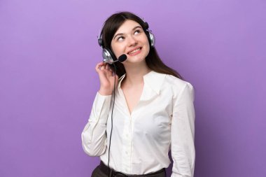 Telemarketer Russian woman working with a headset isolated on purple background thinking an idea