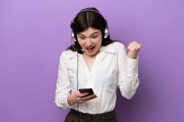 Mor arka planda izole edilmiş bir kulaklıkla çalışan pazarlamacı Rus kadın şaşırdı ve bir mesaj gönderiyor.