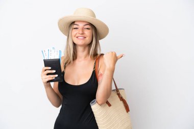 Mayo giymiş genç bir kadın beyaz arka planda izole edilmiş bir pasaport taşıyor. Ürünü sunmak için yan tarafa bakıyor.