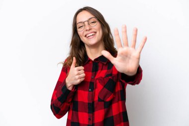 Beyaz arka planda izole edilmiş beyaz tenli genç kadın parmaklarıyla altısını sayıyor.