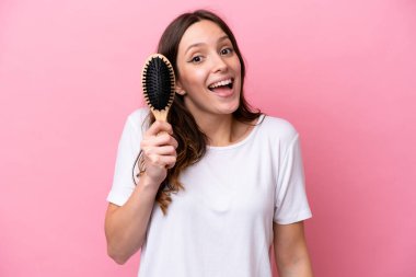 Pembe arka planda saçları taranmış, şaşırmış ve şok olmuş yüzü olan beyaz bir kadın.