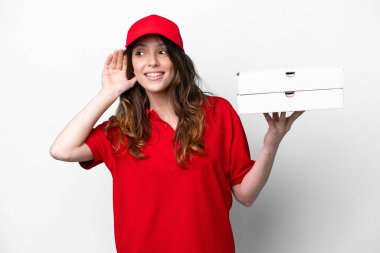 İş üniformalı bir pizzacı kadın beyaz arka planda izole edilmiş pizza kutuları alıyor. Kulağına elini sürerek bir şey dinliyor.