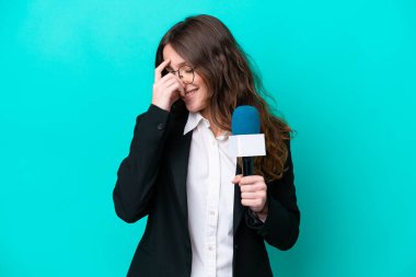 Genç TV sunucusu kadın mavi arka planda izole edilmiş gülüyor.