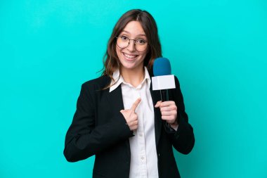 Young TV presenter woman isolated on blue background with surprise facial expression