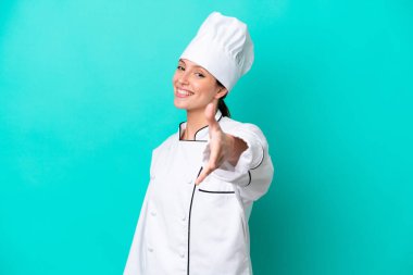 Kafkasyalı genç aşçı kadın mavi arka planda izole edilmiş ve iyi bir anlaşma için el sıkışıyor.